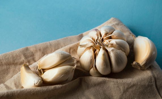 Indian spices Close-up of organic garlic cloves and bulb on rustic burlap with a blue background. Perfect for culinary or organic themes.